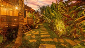 A well-lit garden pathway with stone steps leading to a wooden structure with decorative railings.