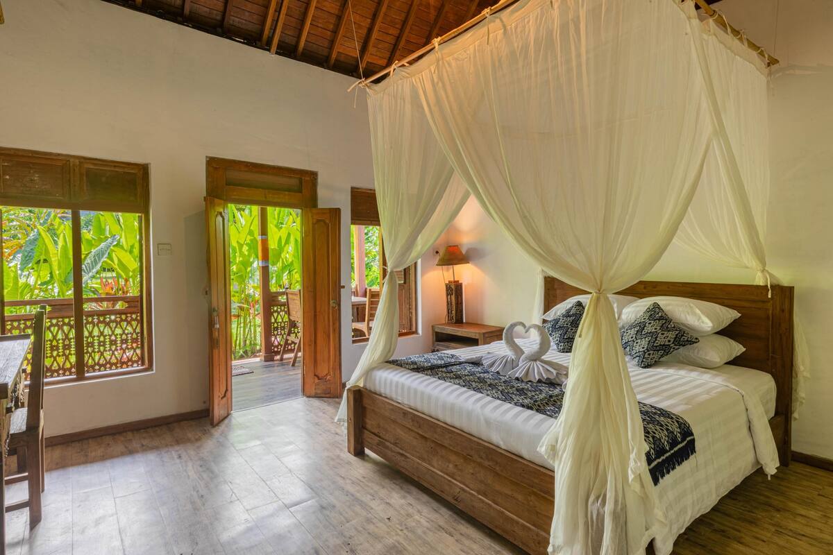 A bedroom with a wooden bed, white canopy, and heart-shaped pillows.