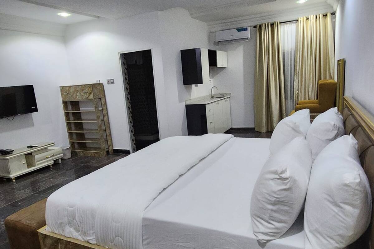 A hotel room with a large bed, a TV, a wardrobe, a desk, and a bathroom.