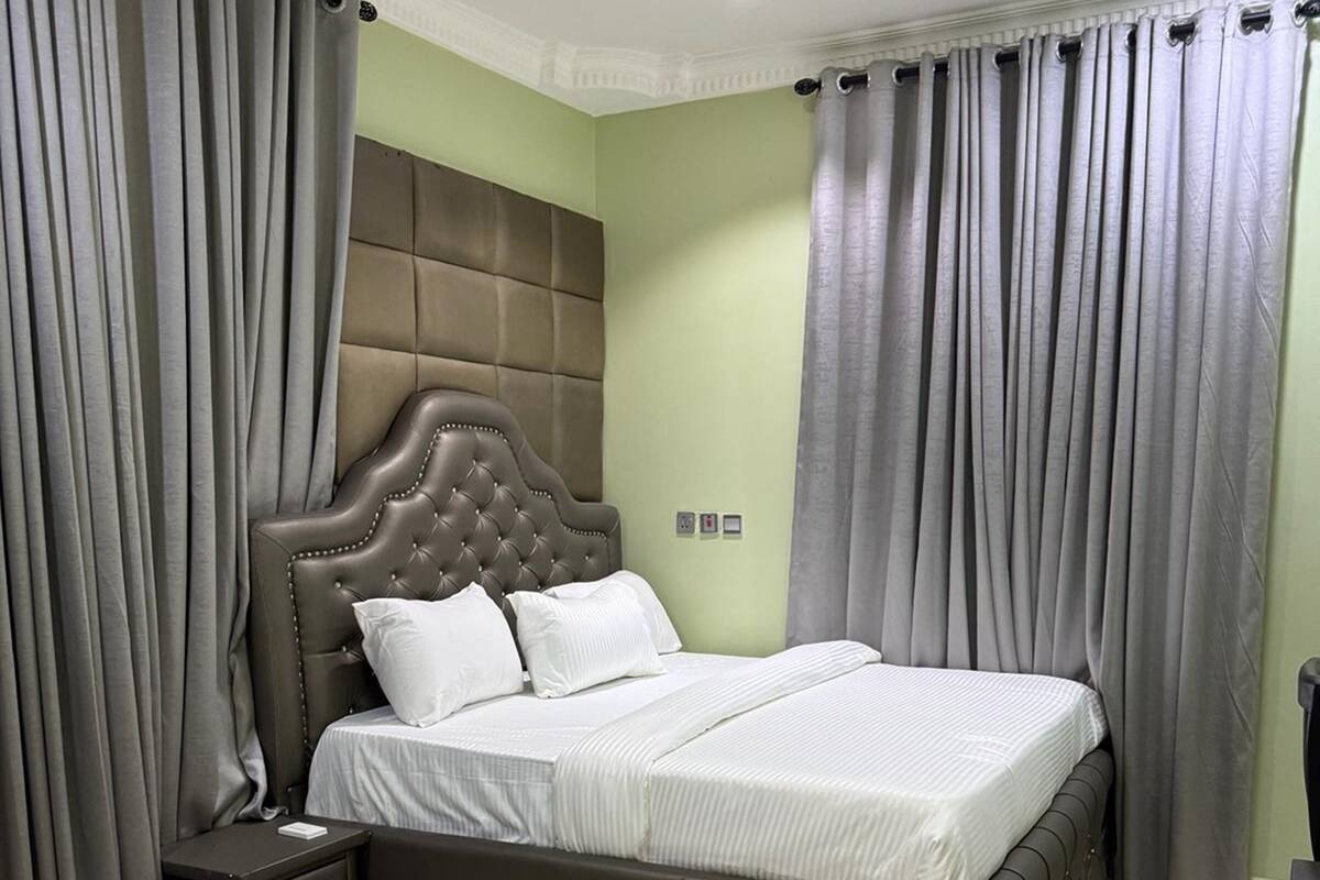A bedroom with a large bed, a nightstand, and a headboard.