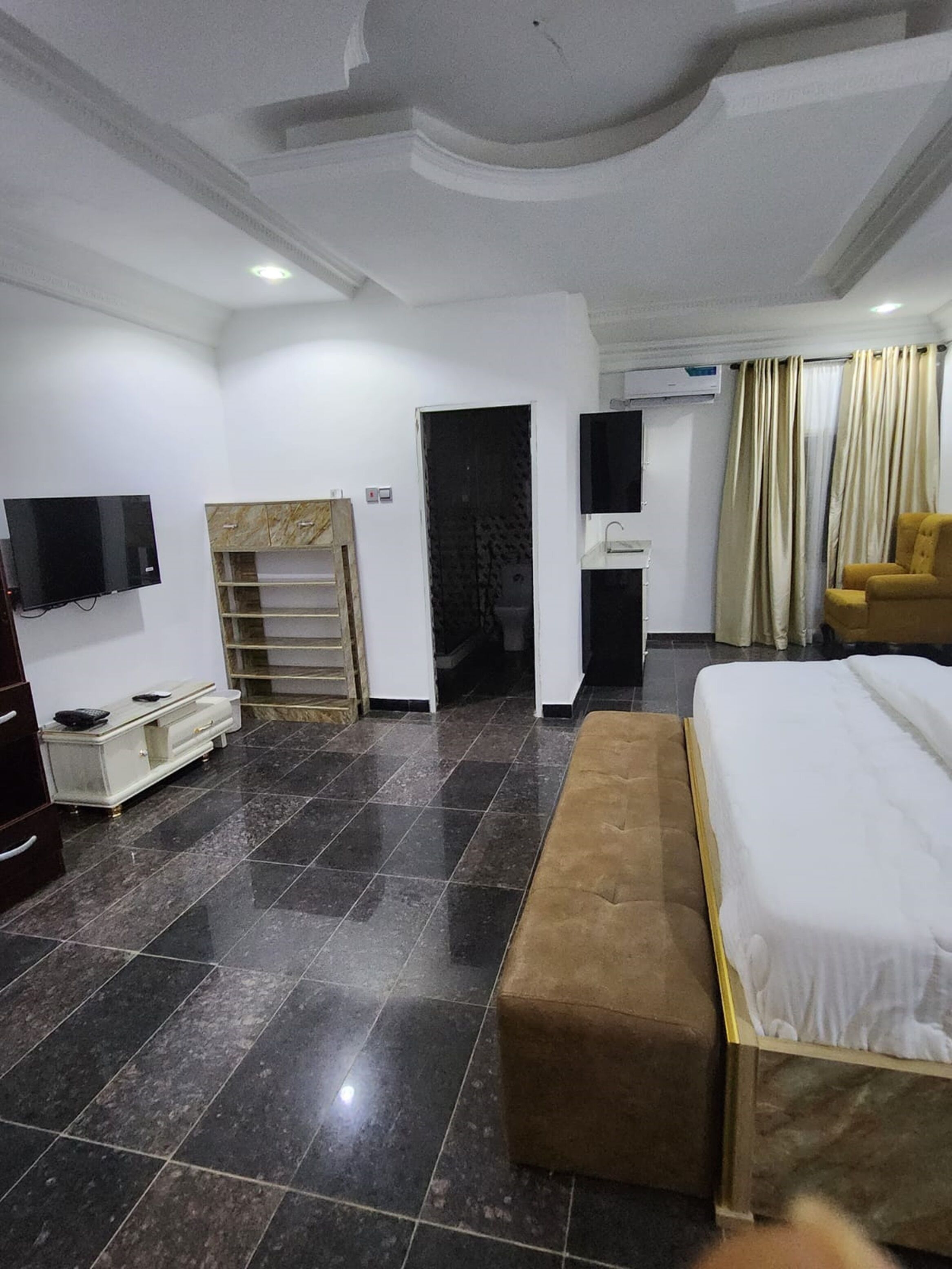 A hotel room with a bed, a TV, a wardrobe, a desk, and a chair.