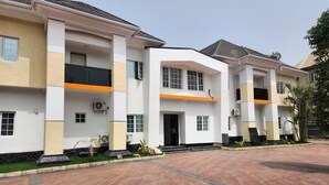 A multi-story residential building with a flat roof, large windows, and a central entrance. - Cozy Residence (Abuja)