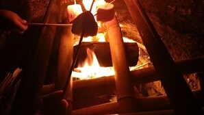A person roasting marshmallows over a campfire in a rustic setting. - Campo Duro ecolodge (Tomás de Berlanga)