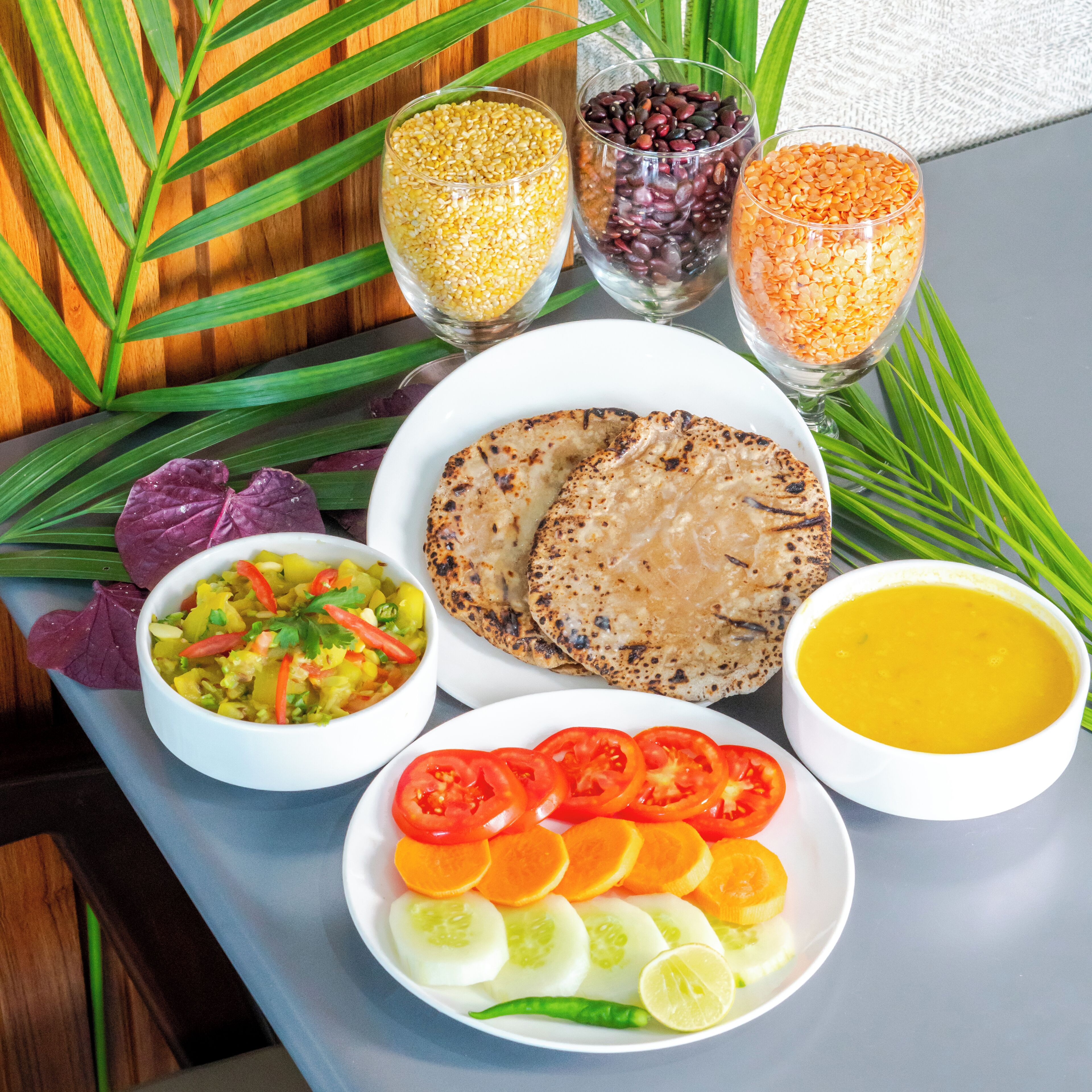 A meal with flatbreads, a vegetable dish, a soup, and a fruit plate.