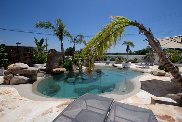 Una piscina rodeada de rocas y palmeras.