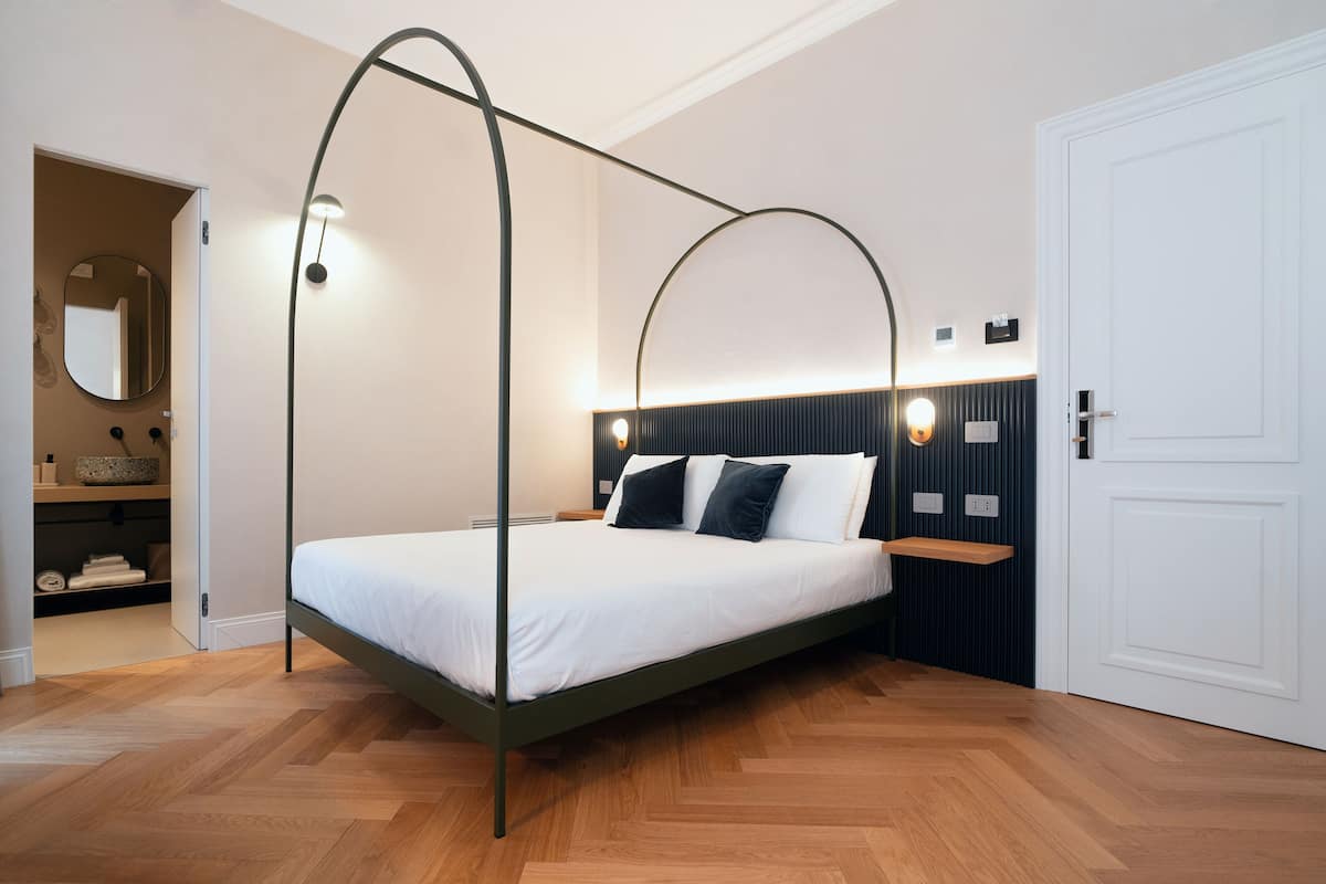 A modern bedroom with a four-poster bed, a bedside table, and a built-in shelf.