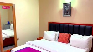 A hotel room with a bed, a nightstand, a framed picture on the wall, and a 'No Smoking' sign on the door. - Prismar International Hotel (Uyo)