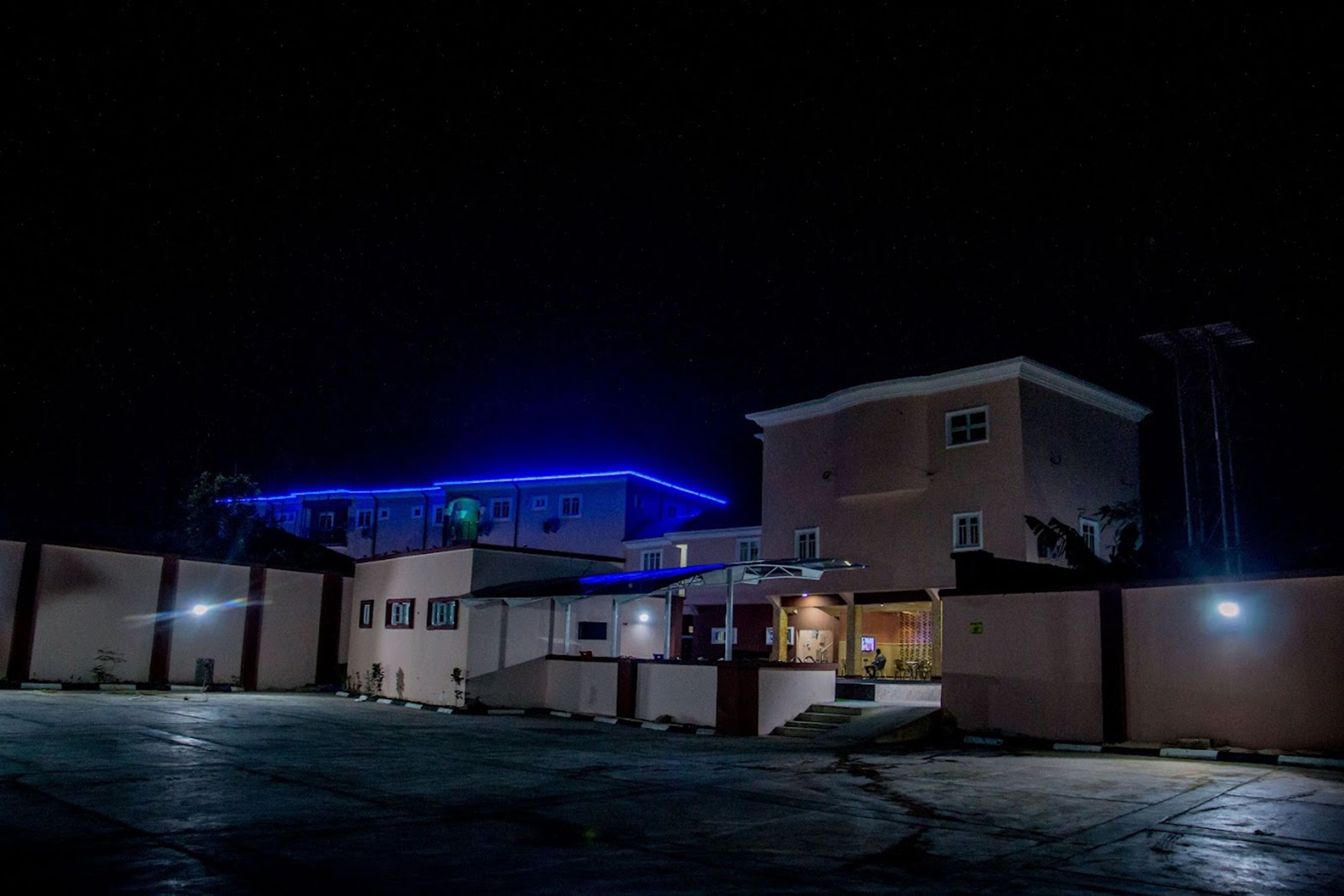 A building with a flat roof, a covered entrance, and a paved courtyard.
