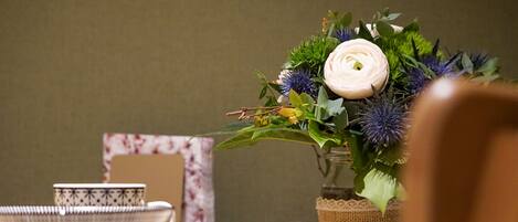A dining table with a vase of flowers, a bowl, a plate, and a napkin.
