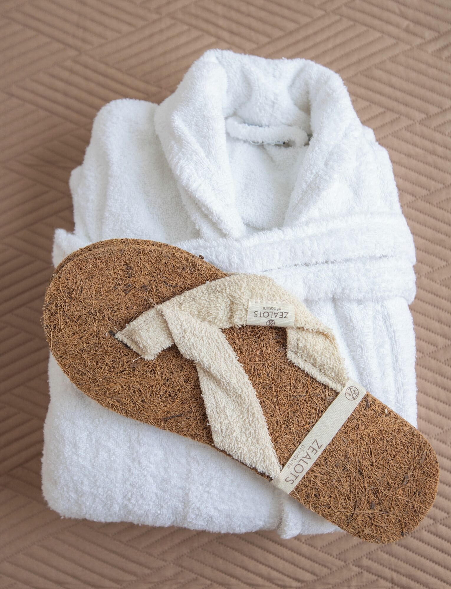 A white bathrobe and a pair of slippers with a label on them.