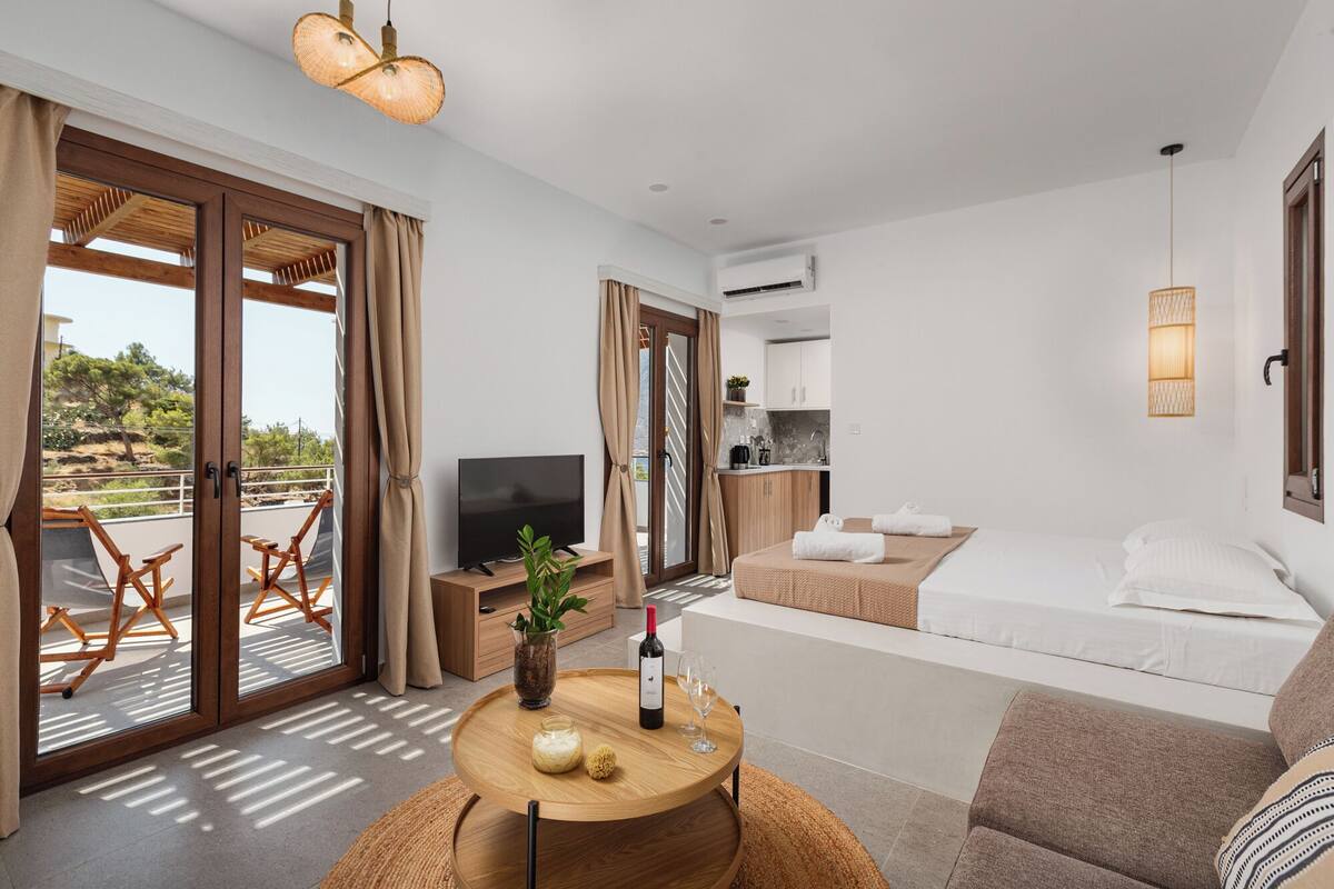 Ein modernes Hotelzimmer mit Balkon, Essbereich und Küchenzeile.