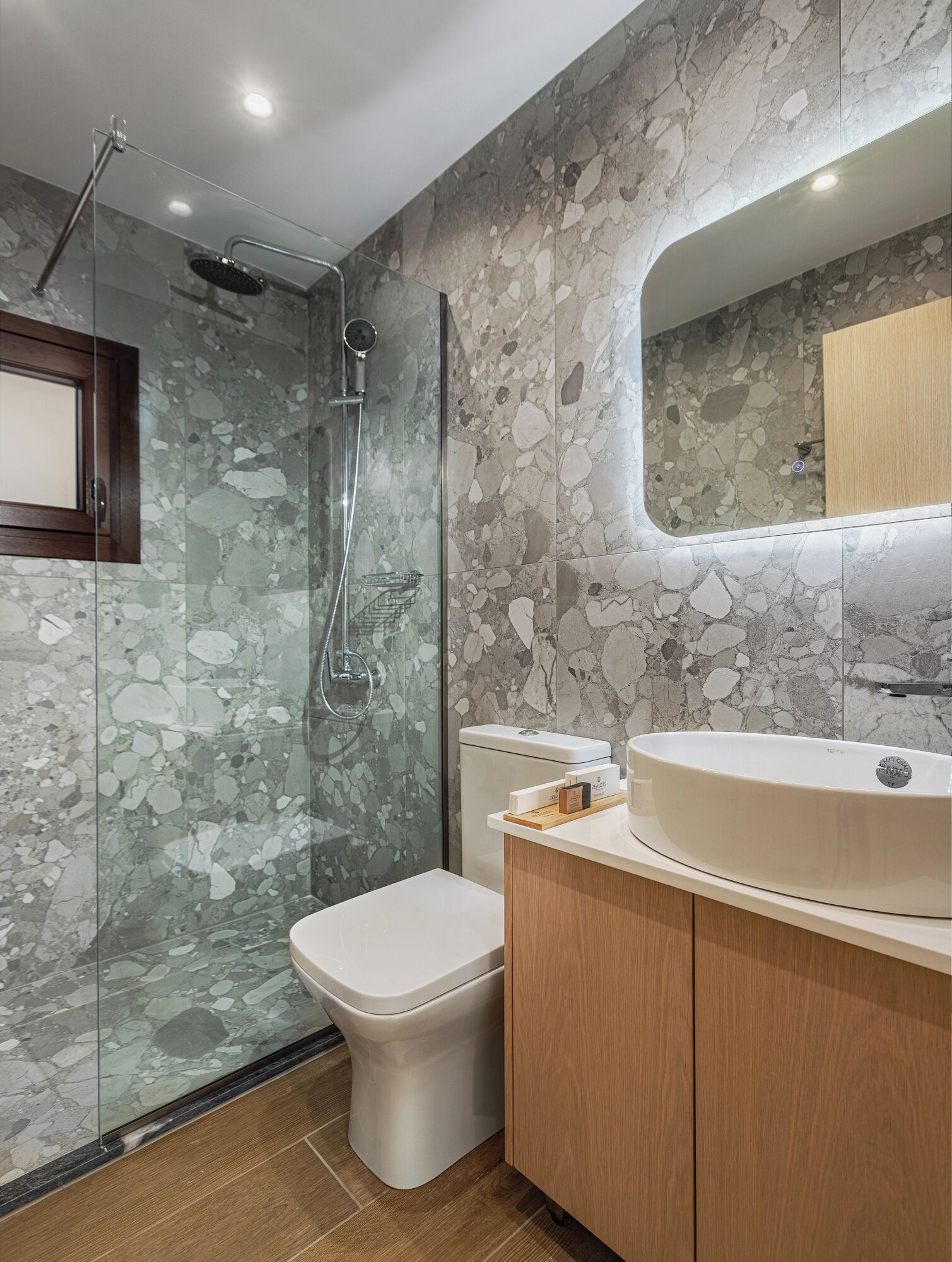 A modern bathroom with a glass-enclosed shower, a toilet, and a vanity with a sink.