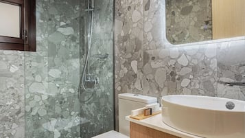 A modern bathroom with a glass-enclosed shower, a toilet, and a vanity with a sink.