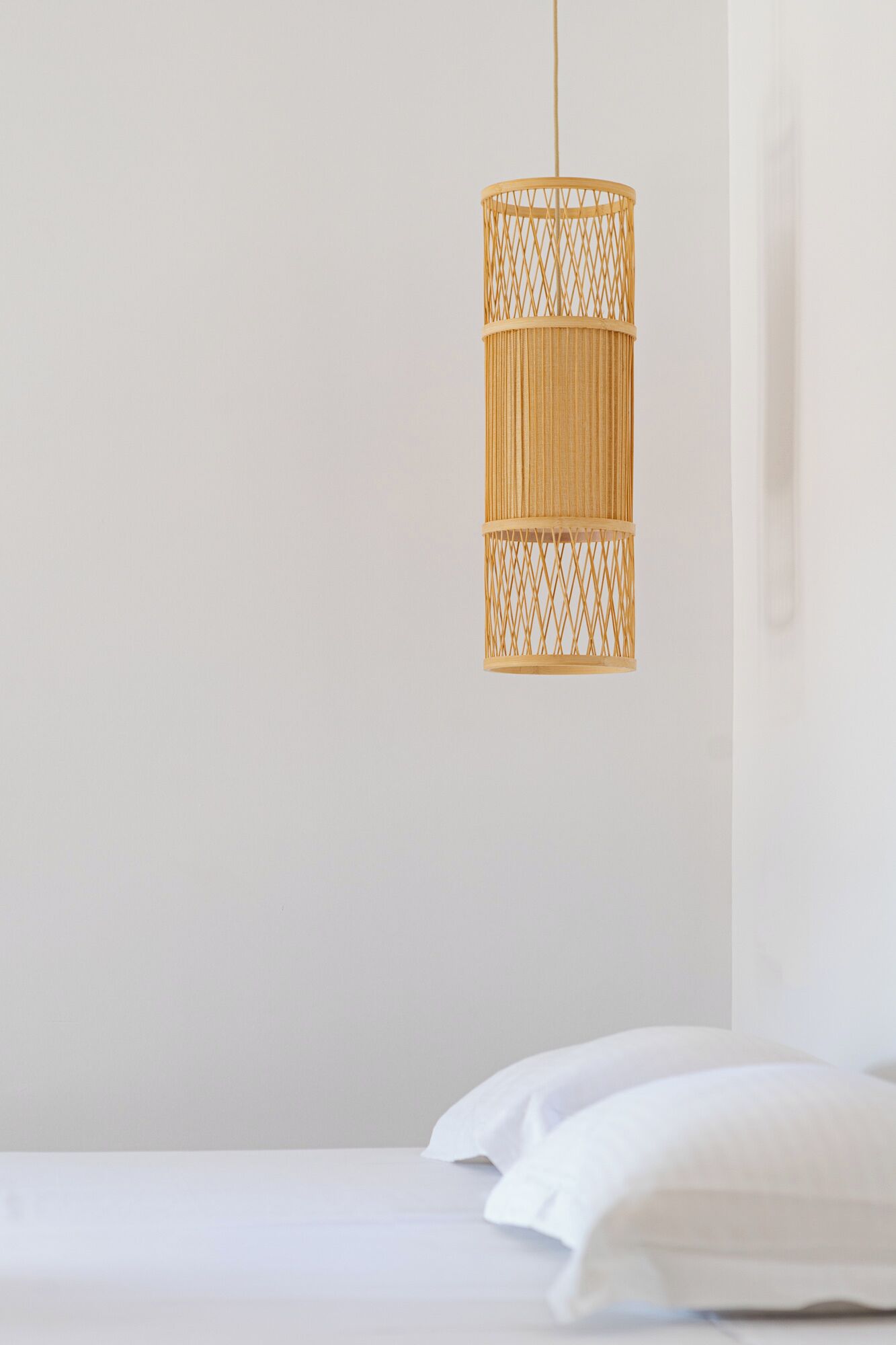 Una habitación sencilla y moderna con cama y una lámpara de mimbre colgante.