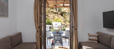 Una sala de estar moderna con dos sofás, una mesa de centro de madera y vistas a una terraza con mobiliario exterior.