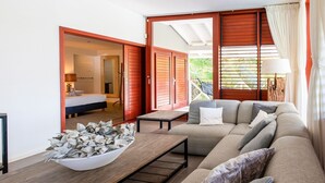 A modern living room with a sofa, a coffee table, and a view of a balcony. - Spacious Villa Near Beach (Jan Thiel)