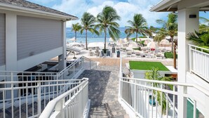 A balcony with a view of a beach, palm trees, and a pool area. - Spacious Villa Near Beach (Jan Thiel)