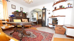 A traditional living room with a fireplace, a large wooden cabinet, a television, and a patterned rug. - Idyllic Villa with Private Pool in Trebusin Czech Republic (Dolní Týnec)