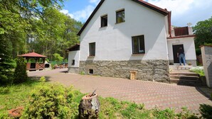 A two-story building with a stone foundation and a white upper section. There is a covered outdoor seating area with a red roof. - Idyllic Villa with Private Pool in Trebusin Czech Republic (Dolní Týnec)