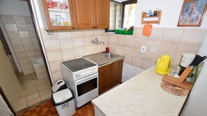 A compact kitchen with a stove, sink, and a small trash bin. - Idyllic Villa with Private Pool in Trebusin Czech Republic (Dolní Týnec)