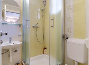Ein Badezimmer mit Duschkabine, Waschbecken in Weiß und Toilette.