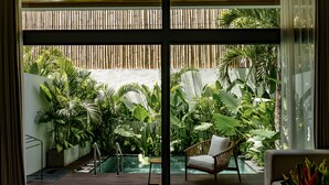 A modern outdoor space with a pool, lush greenery, and a wicker chair. - Sunny Cuddles (Canggu)
