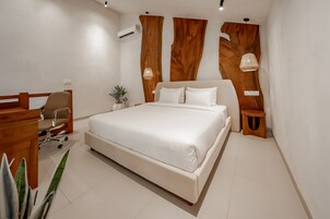 Un dormitorio moderno con una cama grande, cabecera de madera, mesitas de noche y un escritorio con silla.