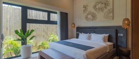 Quarto de hotel moderno com uma cama grande, uma planta em vaso e vista para o verde lá fora.