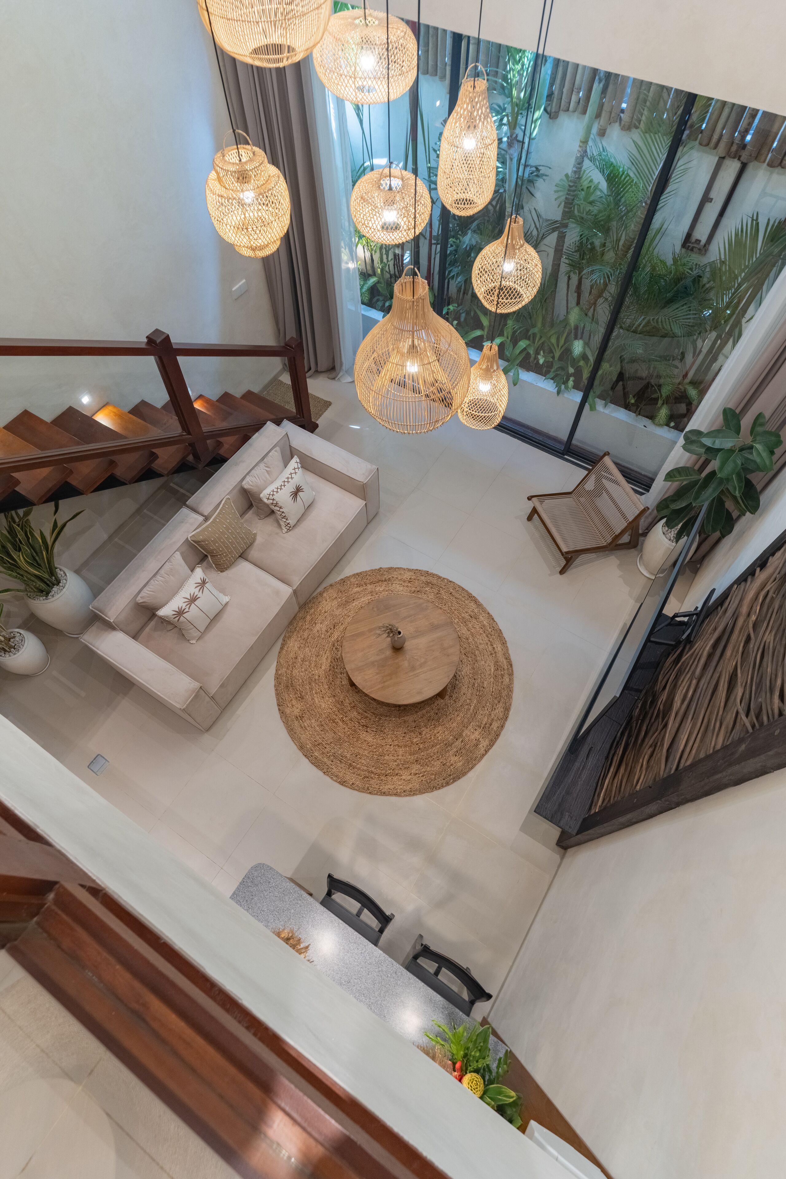 A spacious living area with a sofa set, a round table, and hanging wicker lamps.
