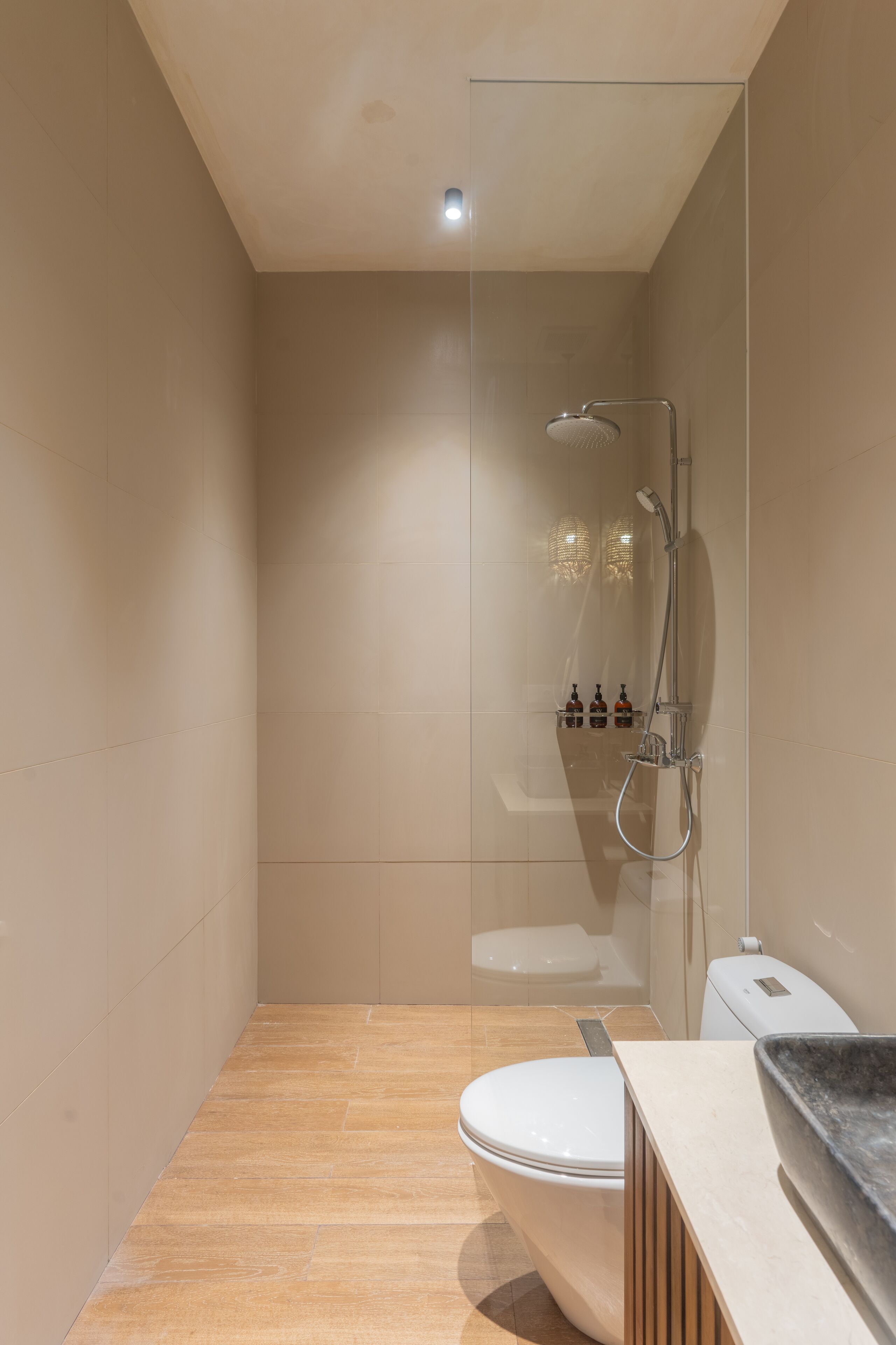 Une salle de bain moderne dotée d’une douche à parois de verre, de toilettes et d’un meuble-lavabo avec un évier.
