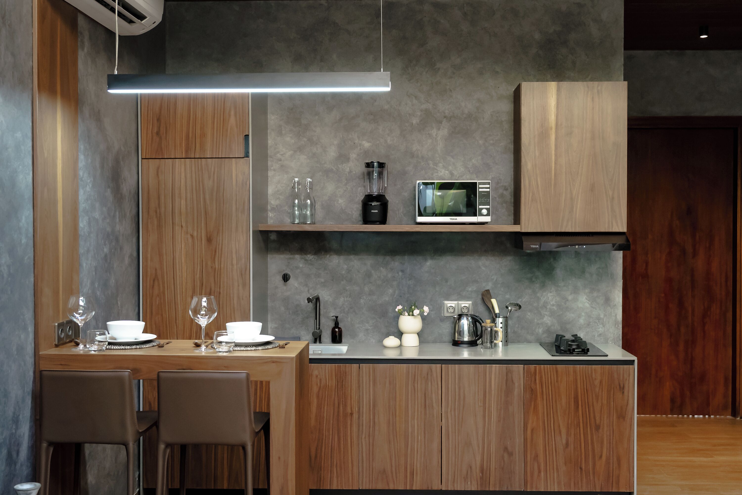 A modern kitchen with wooden cabinets, a microwave, a blender, and a coffee maker.