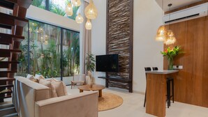 A modern living room with a sofa, a coffee table, a TV, and a small bar area. - Sunny Cuddles (Canggu)
