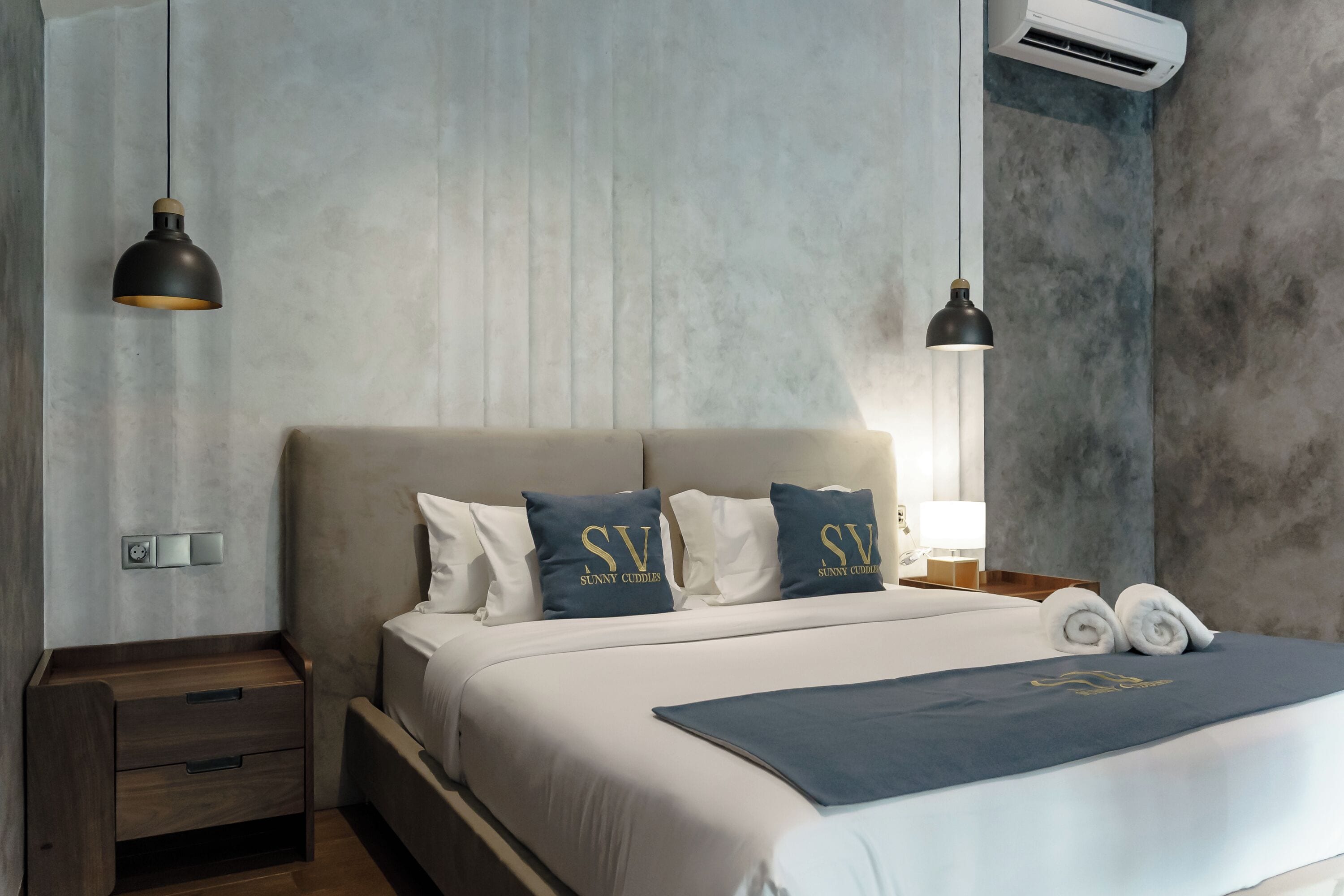 A modern hotel room with a large bed, two bedside tables, and a nightstand.