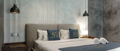A modern hotel room with a large bed, two bedside tables, and a nightstand.
