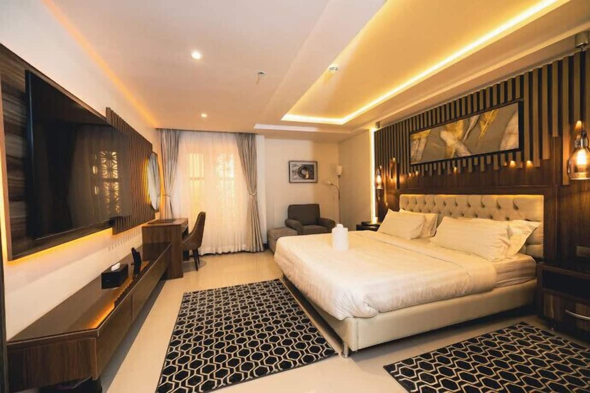 A modern hotel room with a large bed, a TV, a desk, and a chair.