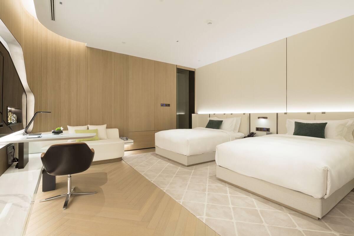 A modern hotel room with a large bed, a desk, and a chair.