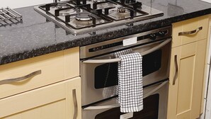 Een keuken met beige kastjes, een zwart aanrecht, een gasfornuis en een oven.