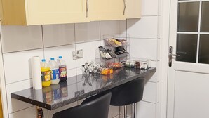 Een keuken met twee zwarte barkrukken, een aanrecht met diverse spullen, en een deur met een raam.