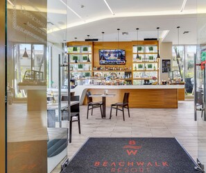 Welcome to our lobby, featuring a reception desk, comfortable seating, and a bar area with a selection of beverages.