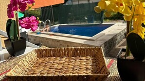 A wicker tray on a balcony with potted flowers and a view of a swimming pool. - Themis Apart Hotel (Kotor)