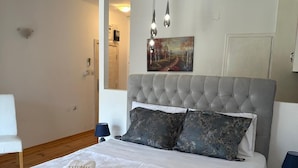 A neatly made bed with a grey headboard, two pillows, and folded towels with "THEMIS" on them. - Themis Apart Hotel (Kotor)