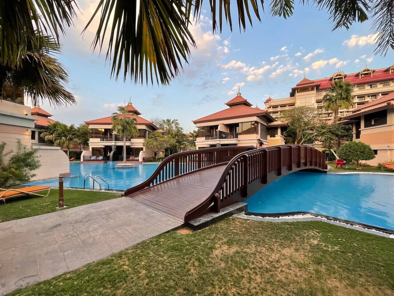 Ein Resort mit Schwimmbad, einer Holzbrücke und mehreren Gebäuden mit roten Dächern.