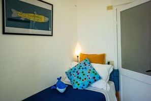 A bedroom with a bed, pillows, a blue plush toy, and a framed picture on the wall. - Maemuna Sea View Apartment (Vernazza)