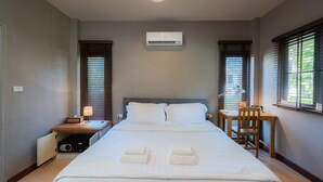 A hotel room with a large bed, a desk, a chair, an air conditioner, and a window with blinds. - Re-Connect Nature Lodge Pai (Pai)