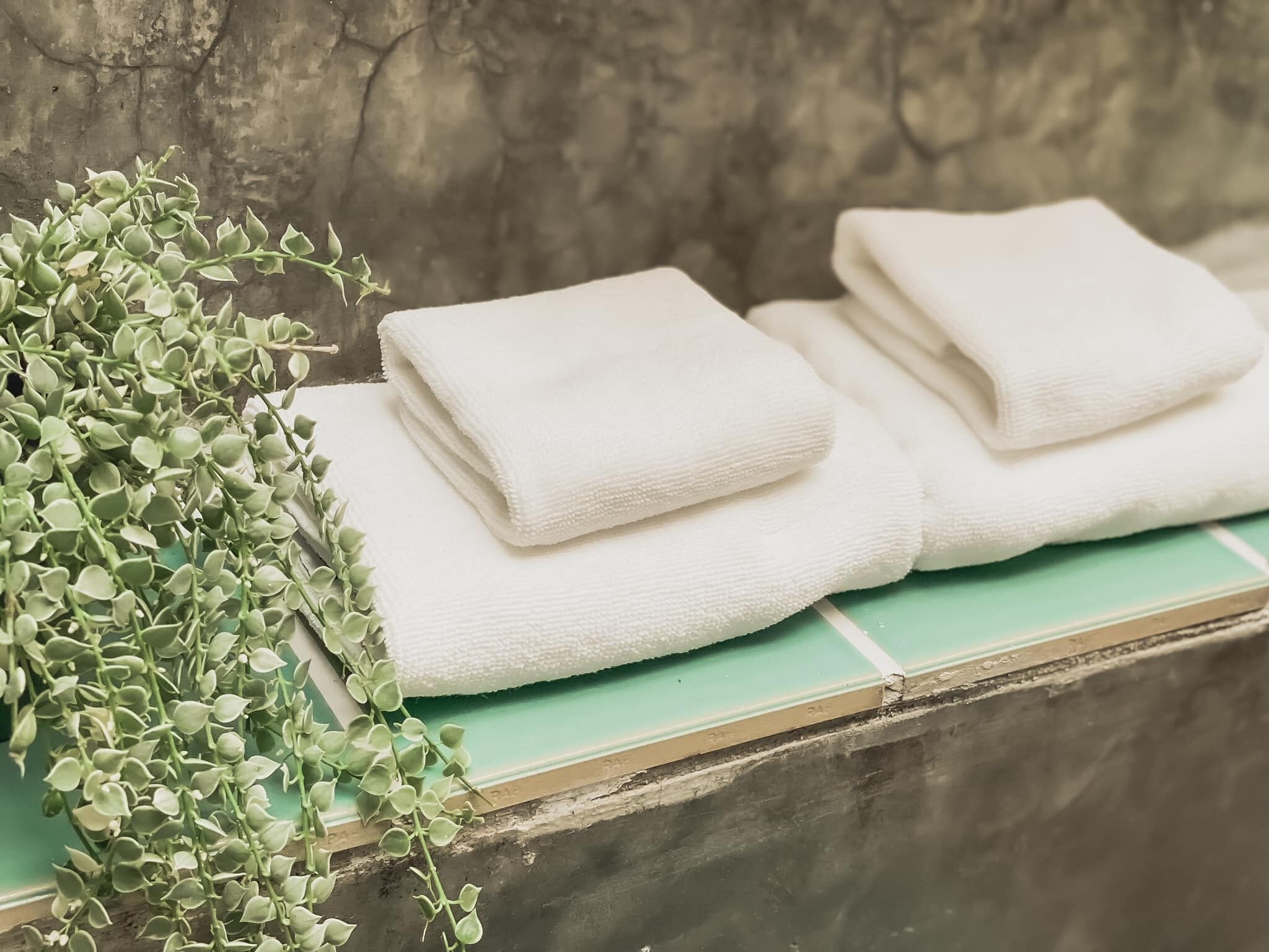 A stack of white towels on a green tiled ledge.