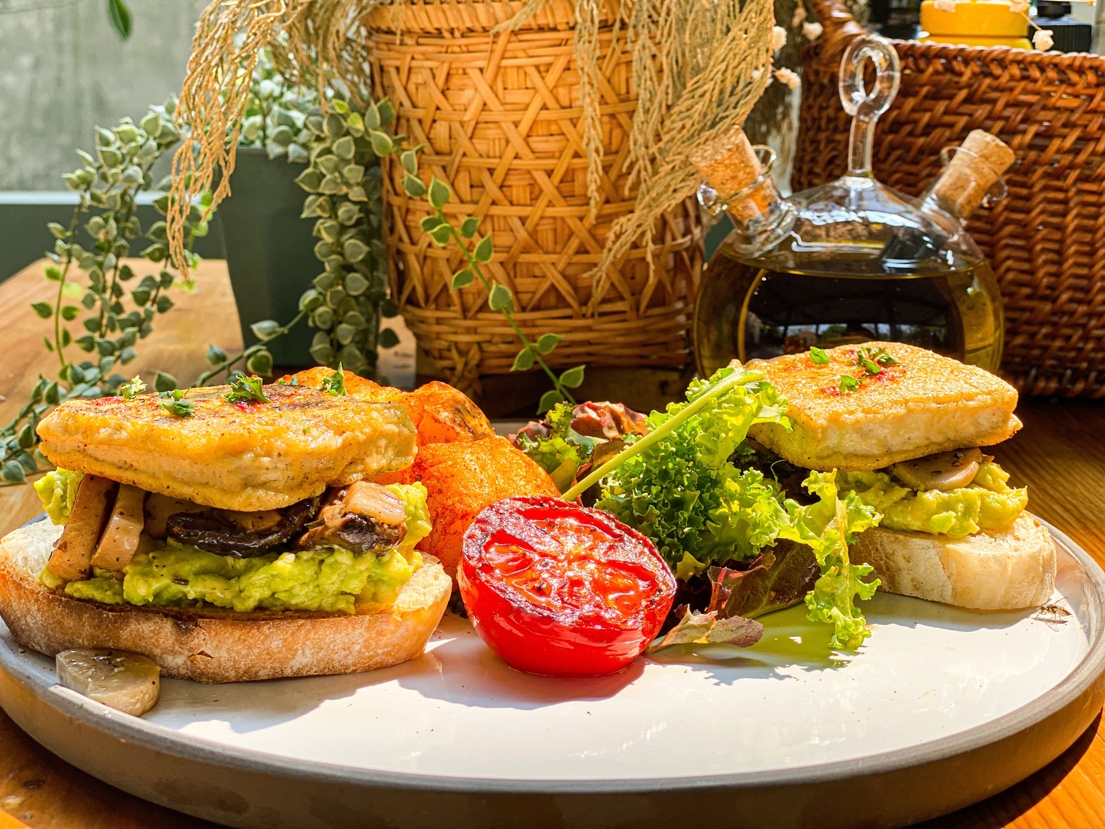 A plate with sandwiches, a tomato, and a salad.