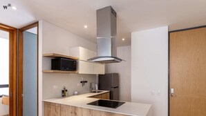 Uma cozinha moderna com ilha central, micro-ondas embutido, eletrodomésticos de aço inoxidável e armários de madeira.