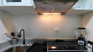 A kitchen with a granite countertop, a stainless steel sink, a black induction cooktop, and a blender. - w * | Elegant 1BR in San Isidro (San Isidro)