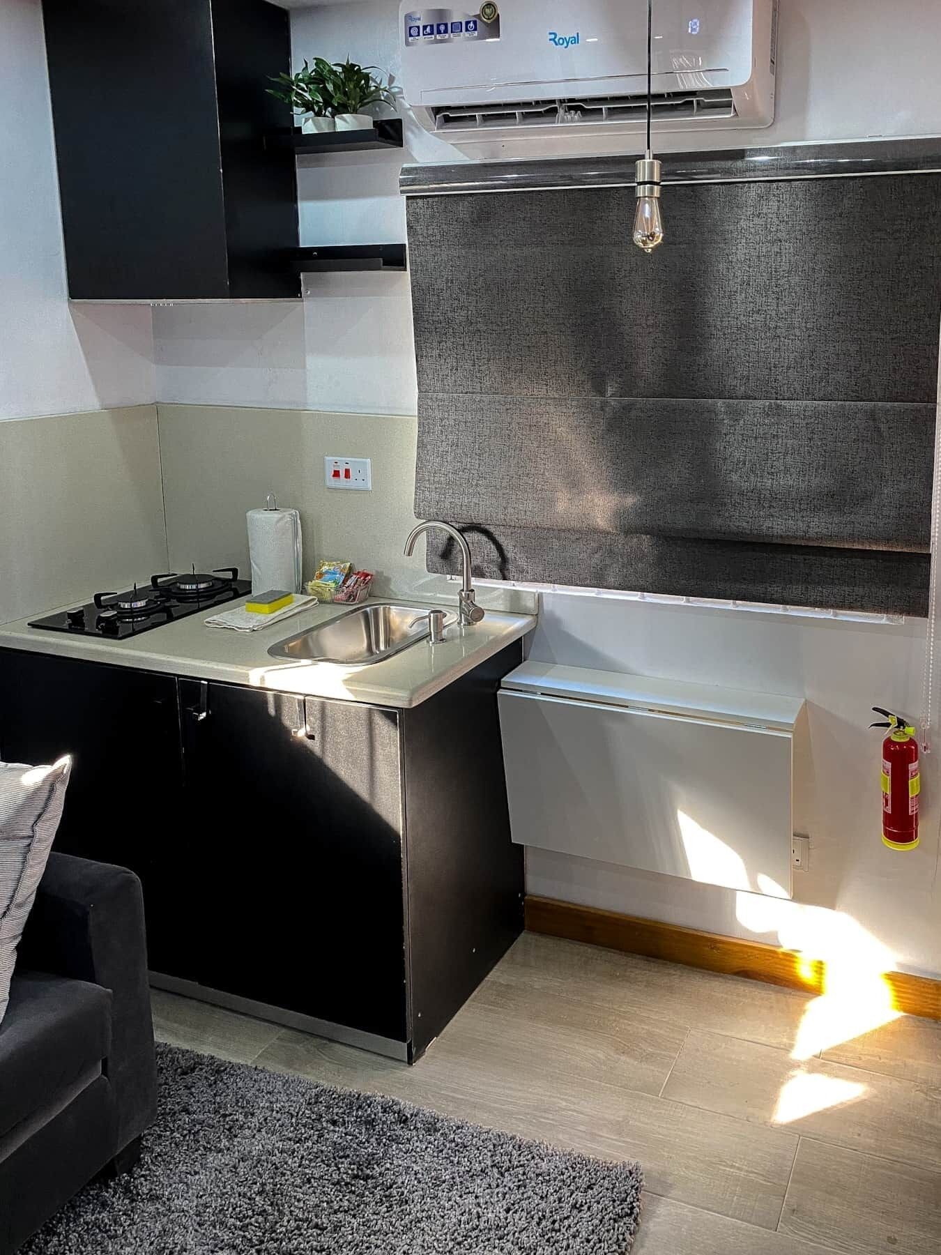 Cocina compacta con estufa a gas, pileta y refrigerador pequeño.
