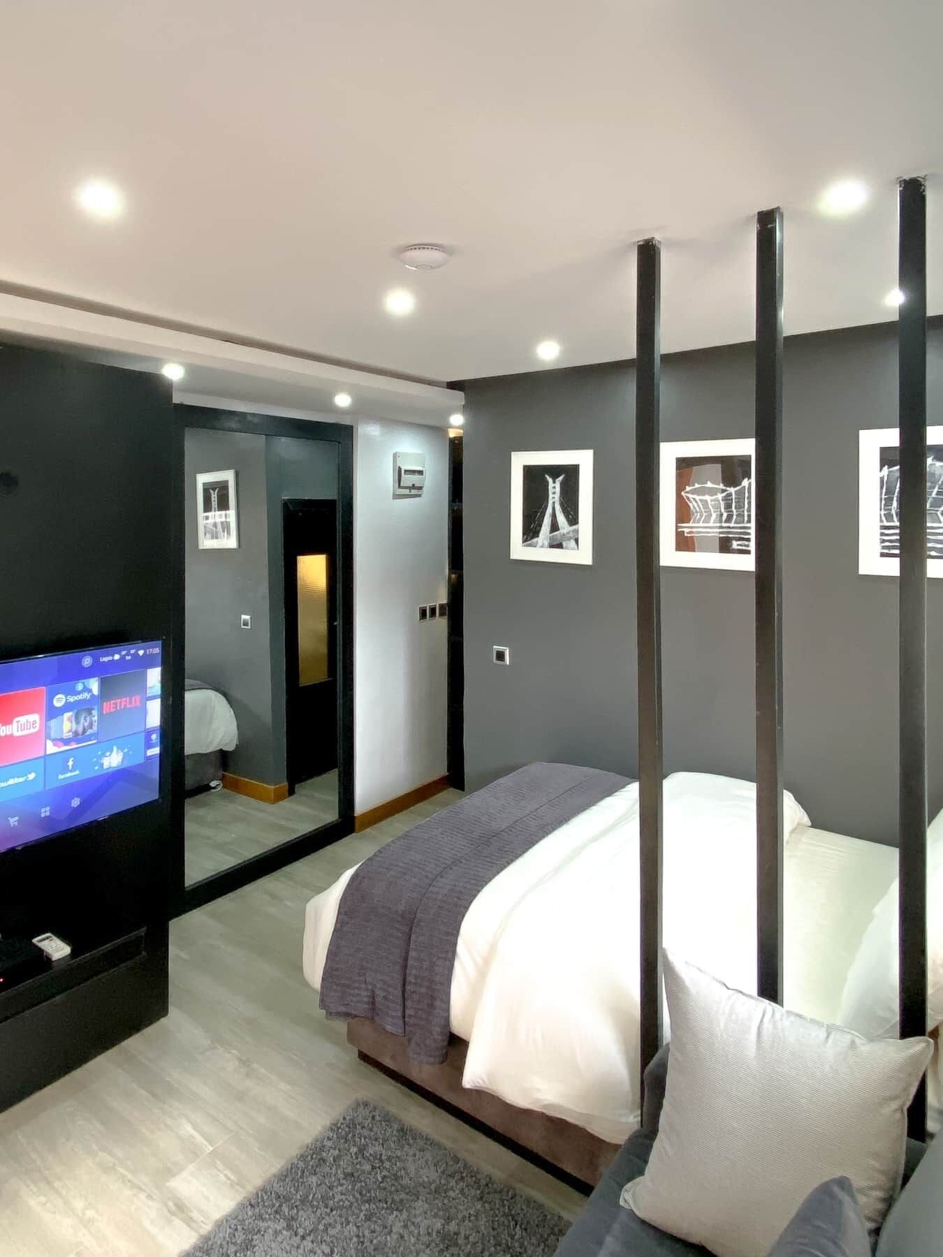 Une chambre à coucher moderne avec un lit, une télévision et un grand miroir.